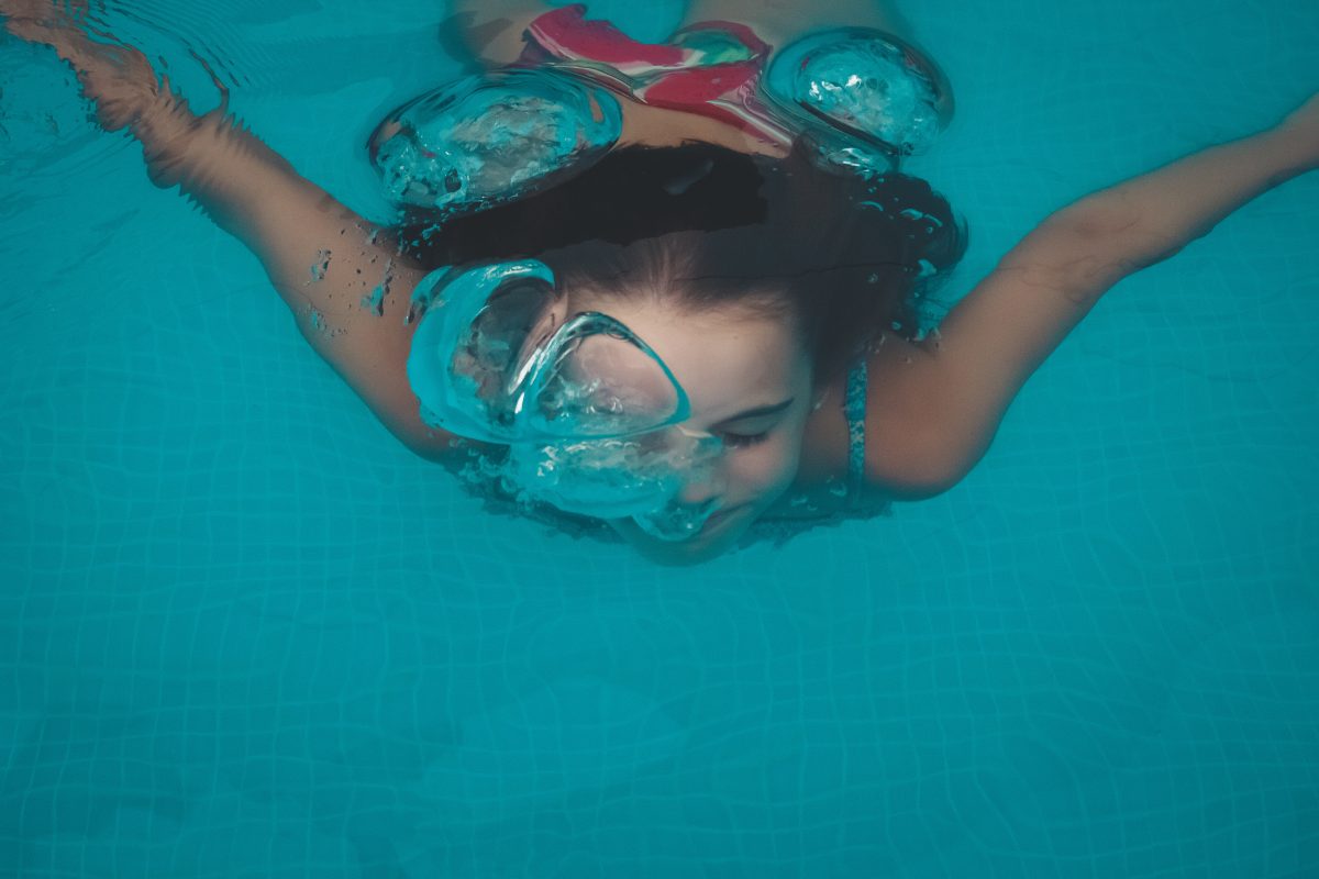 Girl swimming underwater. Swimming a the pool is a low risk activity during the summer of coronavirus, as long as we social distance. Alison Escalante MD